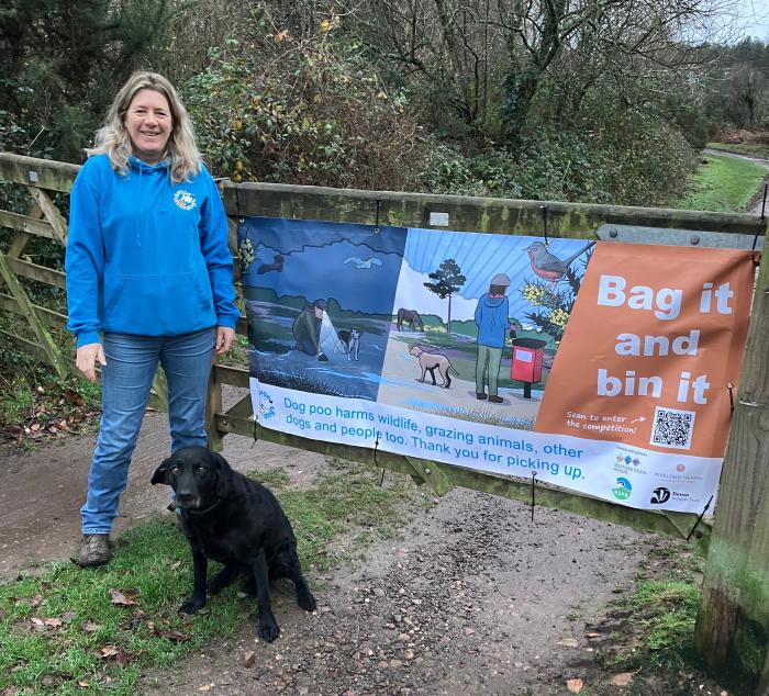 A photo of Julie with dog Maisie in front of one of the campaign banners